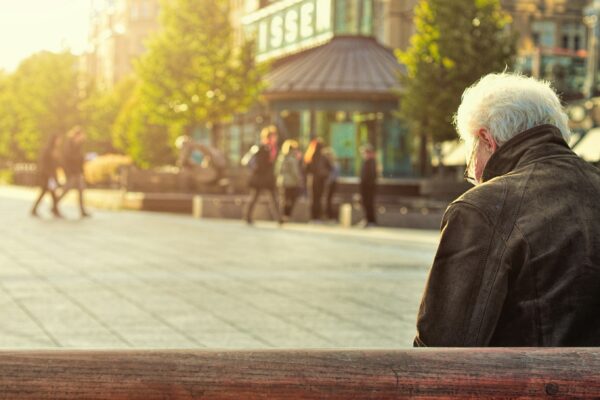 man sitting on brown wooden bench