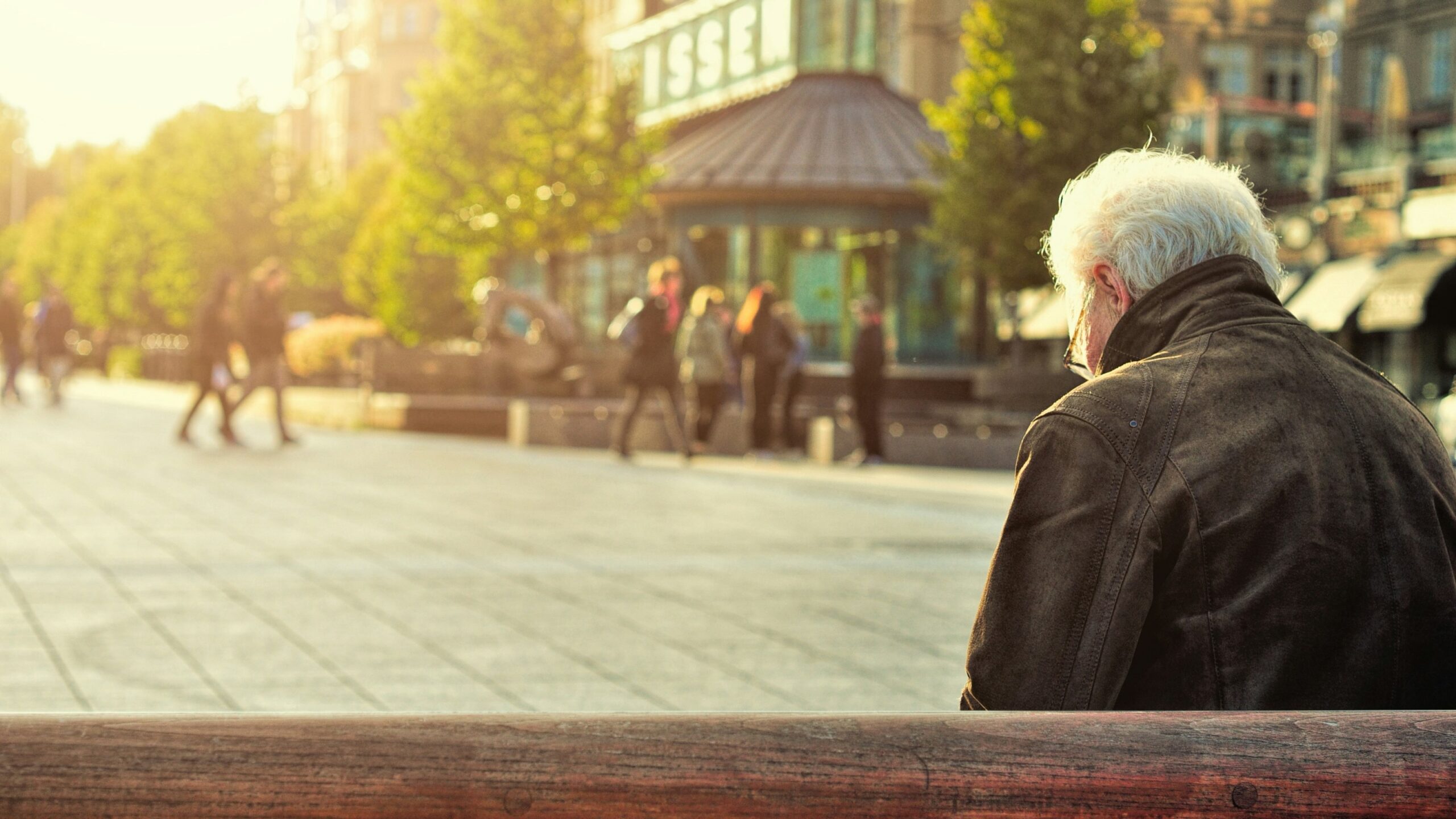 man sitting on brown wooden bench