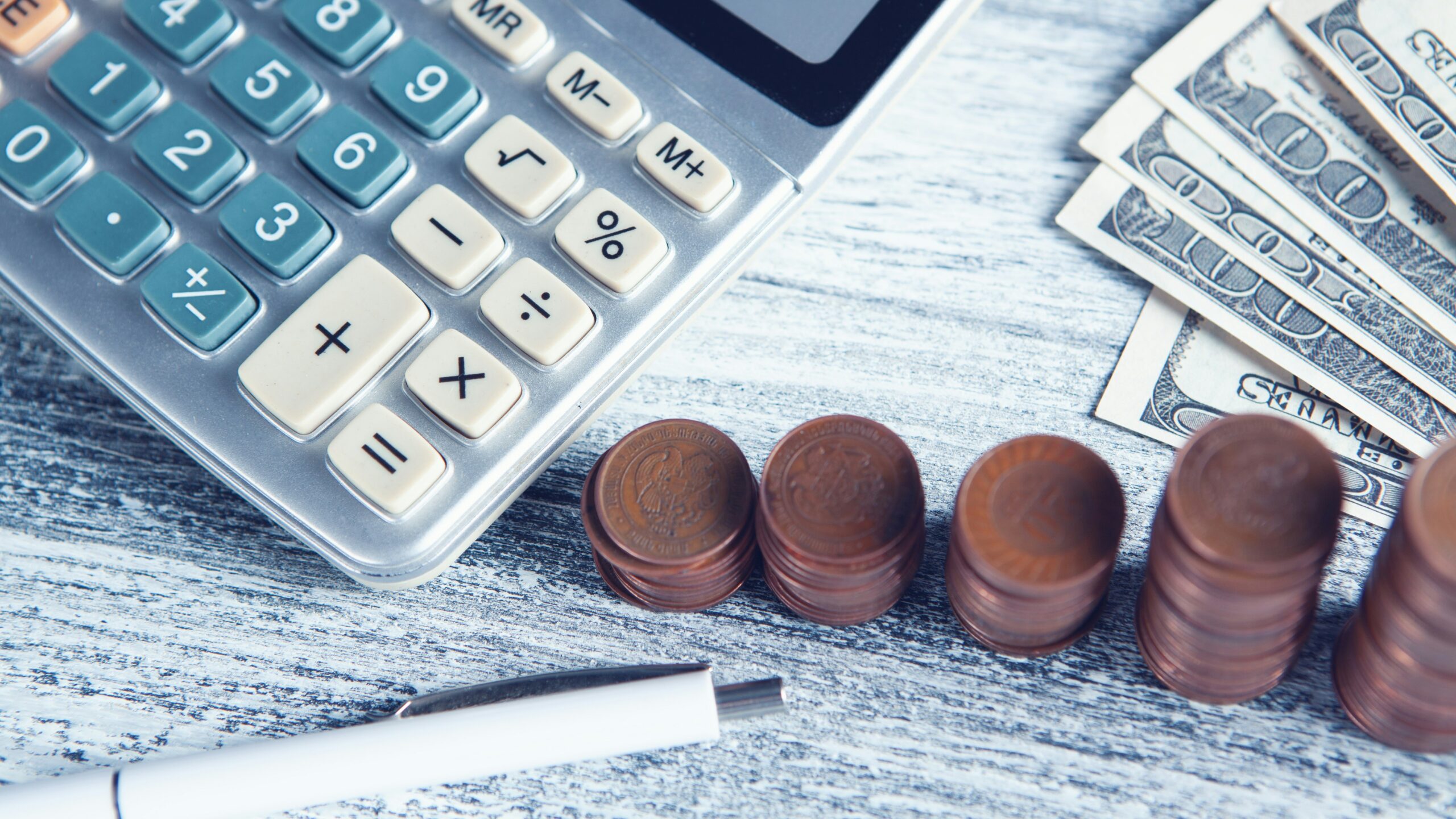 a calculator, pen, and money on a table