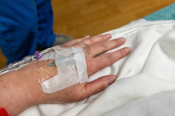 An iv drip is in a patient's hand.