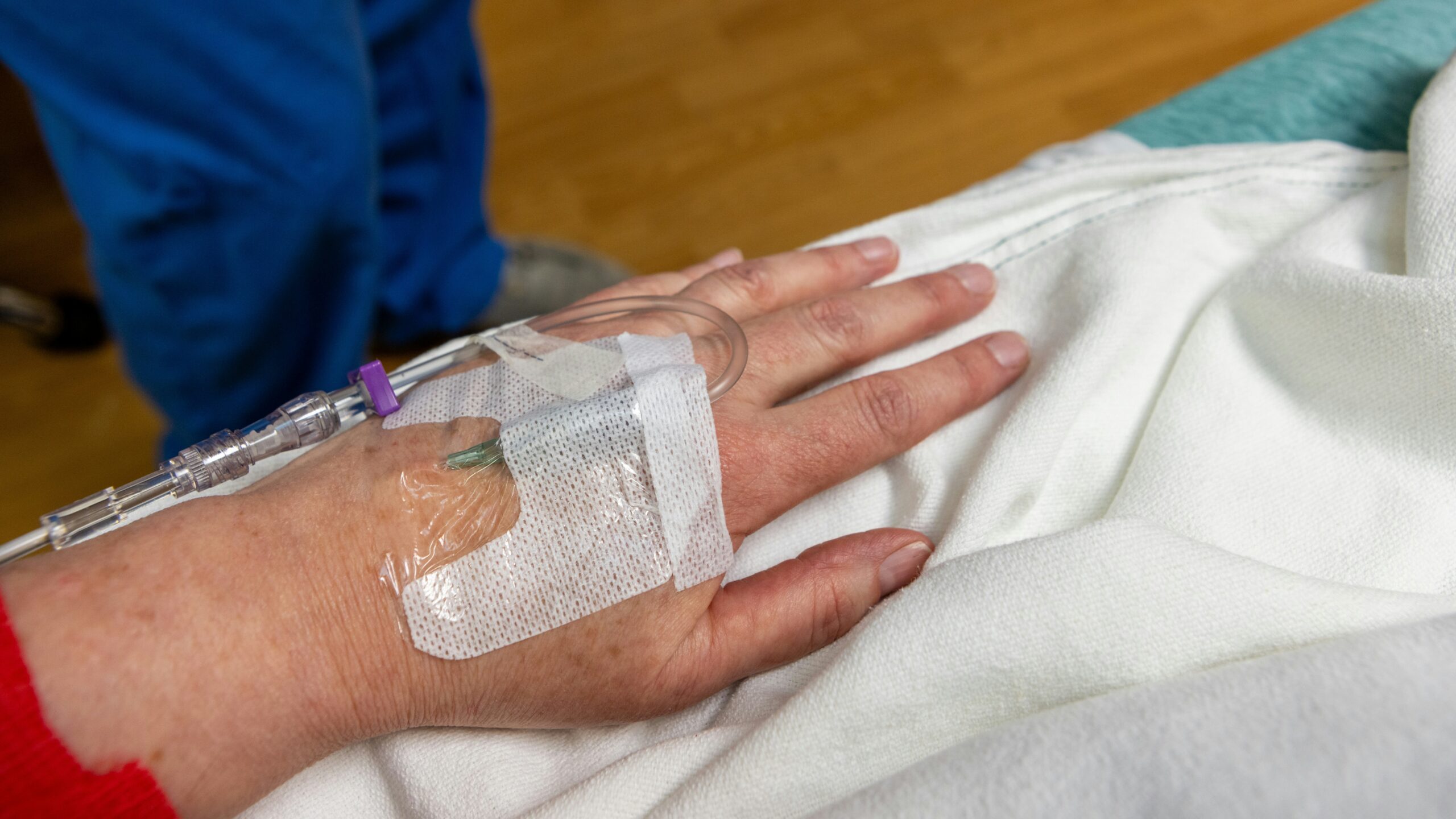 An iv drip is in a patient's hand.