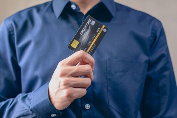 Close-up of a man in a blue shirt holding a credit card, symbolizing finance and security.