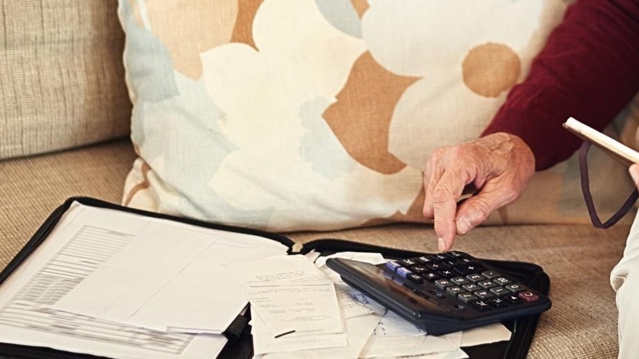 Senior man notebook and calculator on sofa for budget planning and savings account for retirement Elderly person bills and couch in lounge for mortgage personal debt and loan repayment ay home