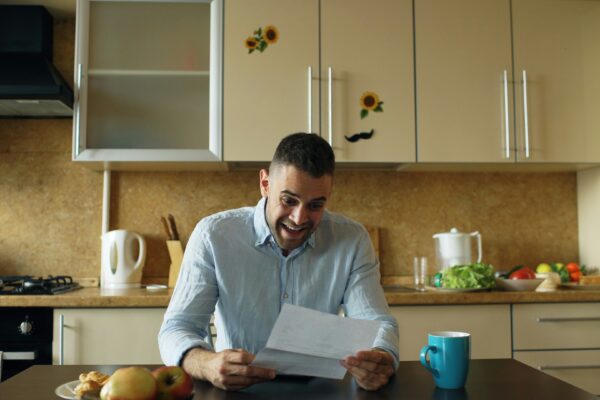 Man reading a letter at a kitchen table.