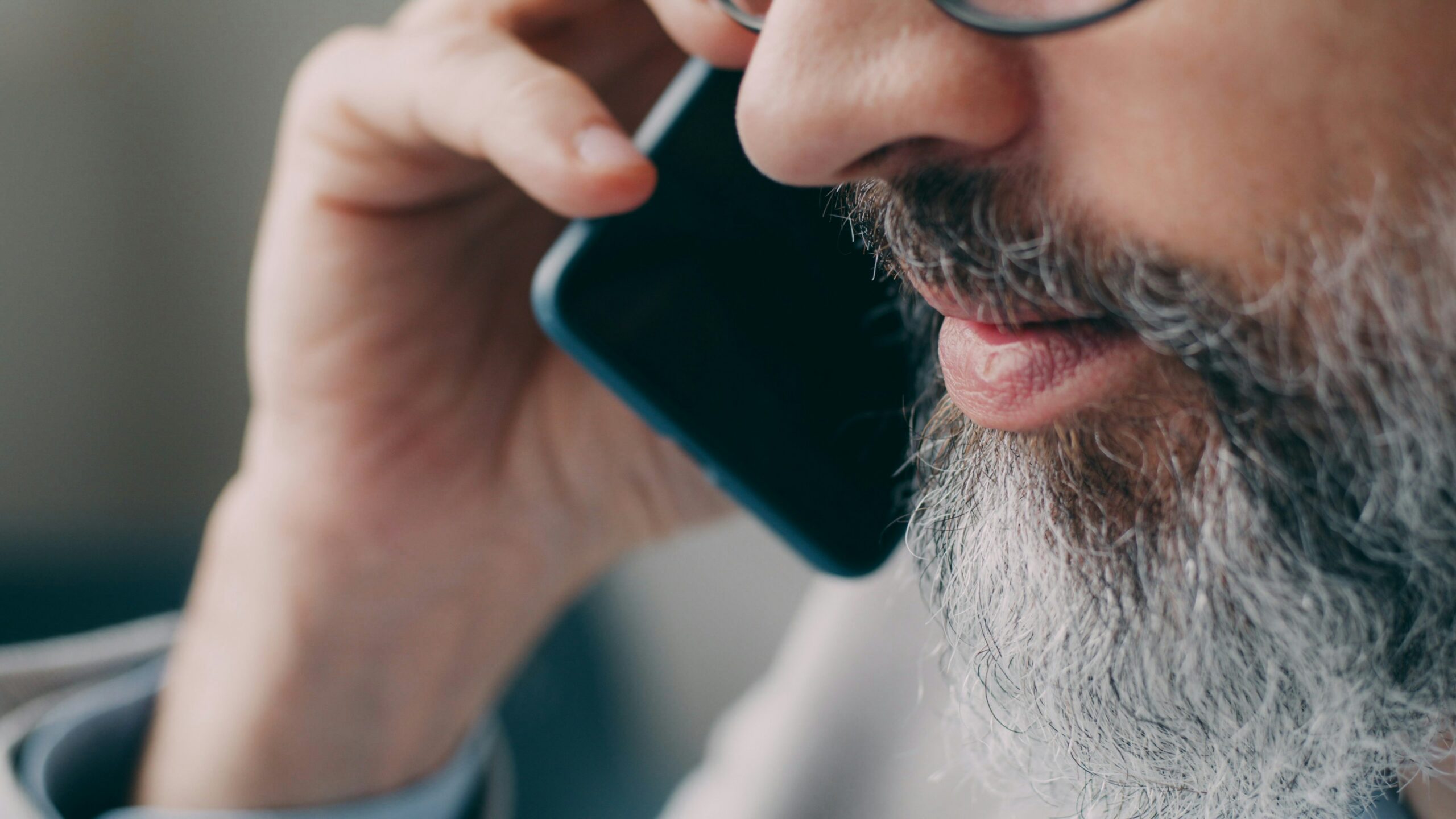 A man with a beard talking on a cell phone