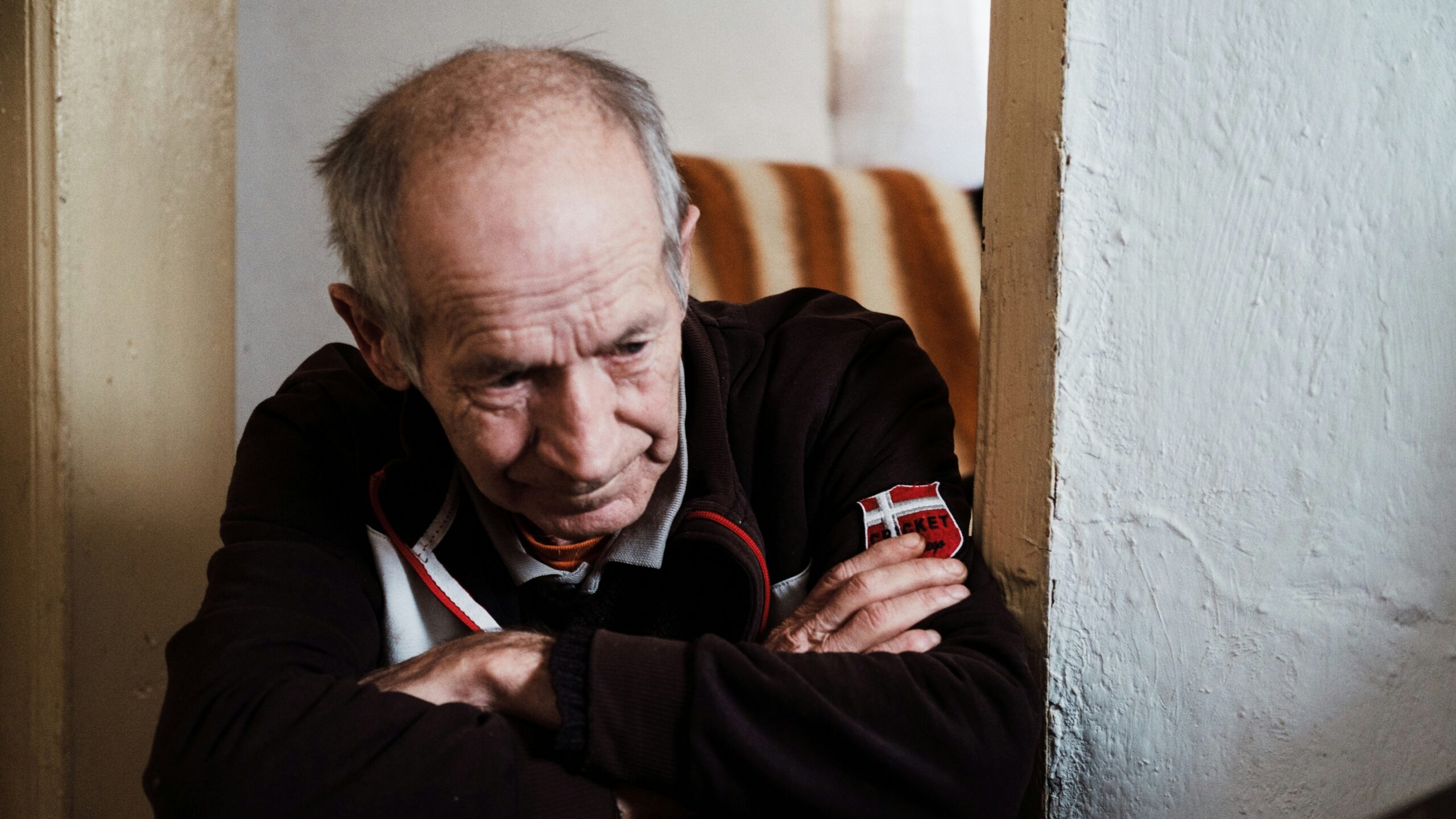man in black jacket sitting on brown wooden chair