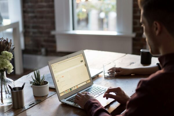 man operating laptop on top of table