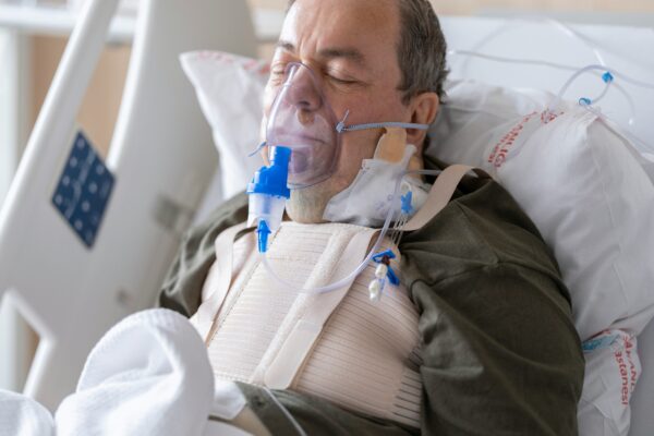 a man laying in a hospital bed with oxygen in his mouth