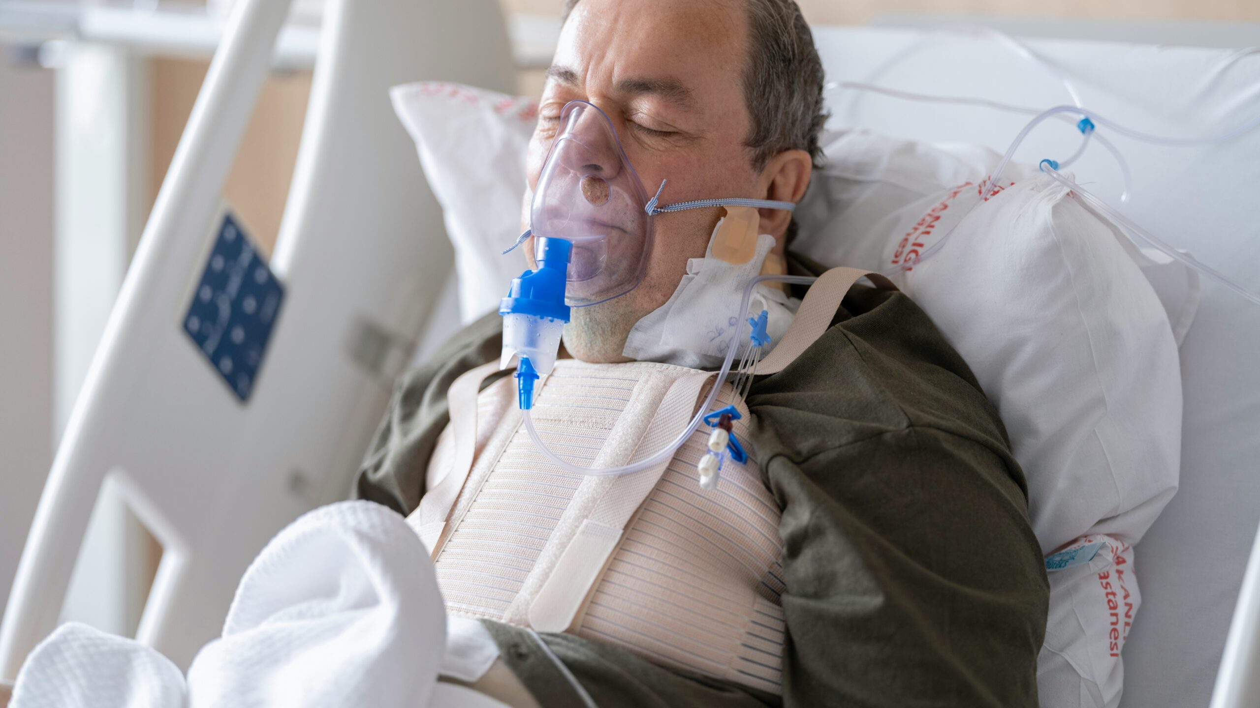 a man laying in a hospital bed with oxygen in his mouth