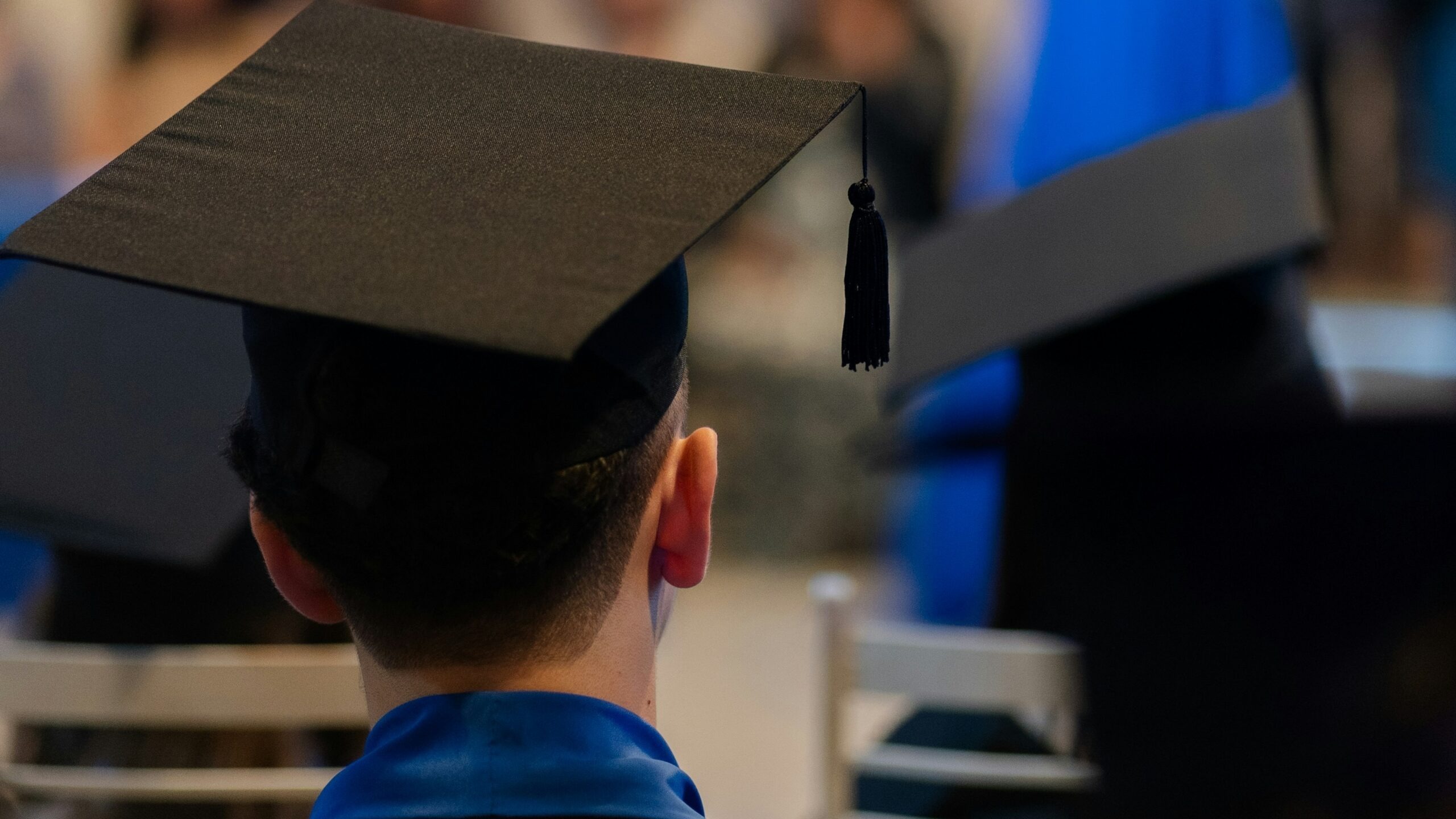 A man in a graduation cap sitting in a chair