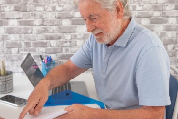 Handsome senior business man in office finishing the contract with a client asking for a signature smiling caucasian people sitting at the desk