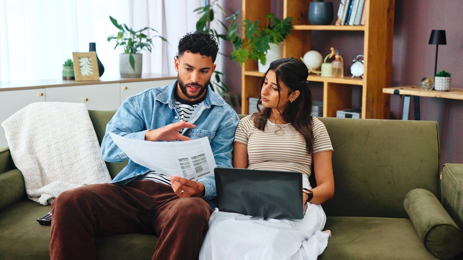 Documents laptop and couple on sofa in home for bills payment receipts and banking Marriage relationship and man and woman with paperwork for financial planning with taxes insurance and budget