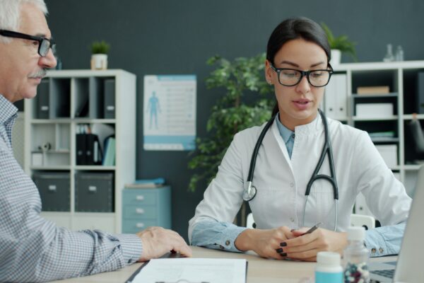 Doctor consulting with an elderly patient in an office.