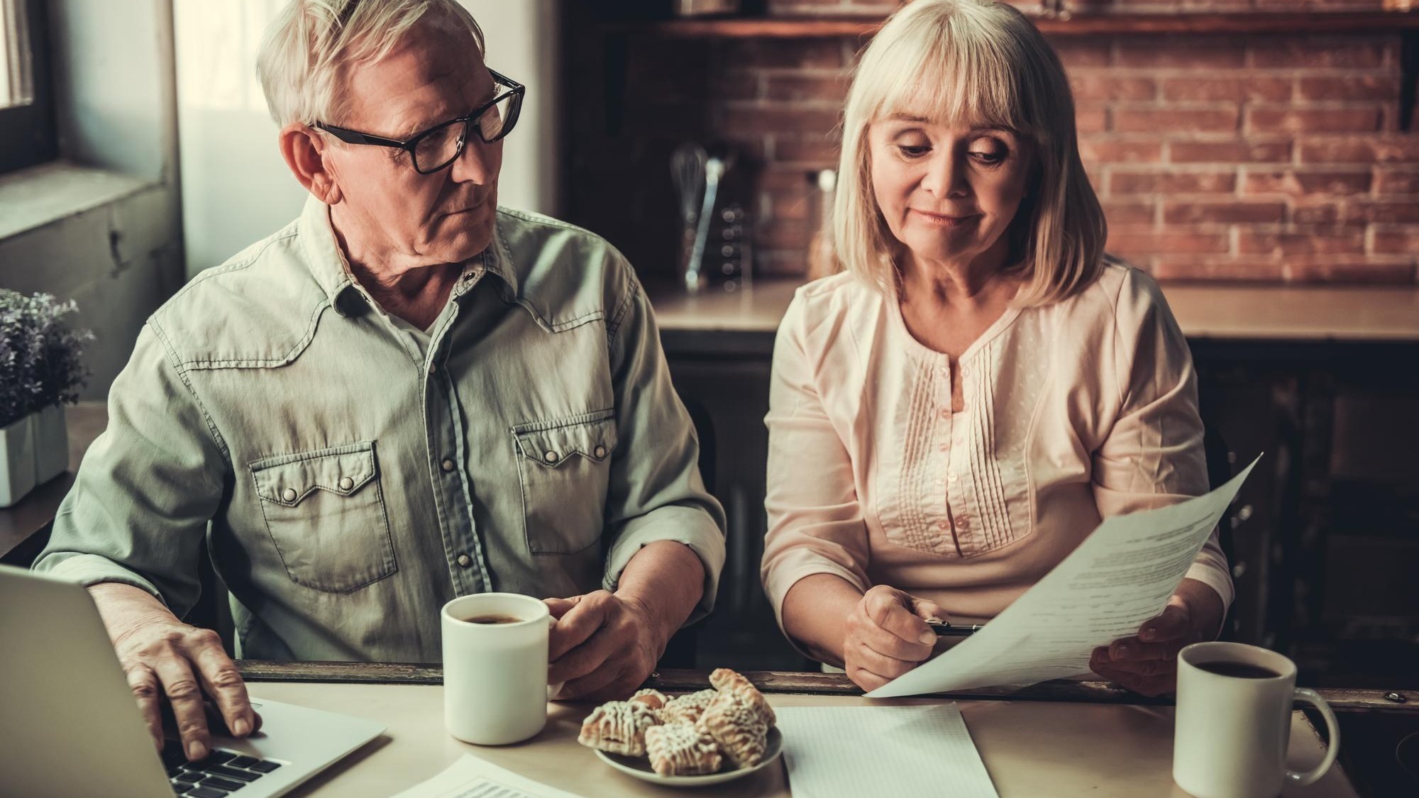 Older couple reviewing documents and using a laptop at home