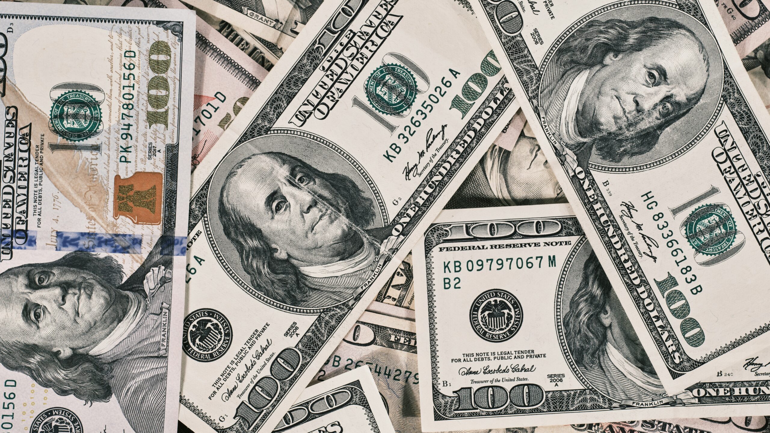 A scattered pile of American one hundred dollar banknotes