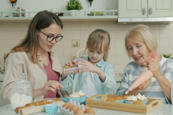 Three women baking and decorating cupcakes in a kitchen