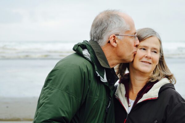man kissing woman on check beside body of water
