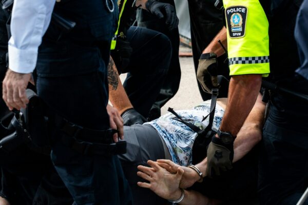 Police officers arresting a man on the ground.