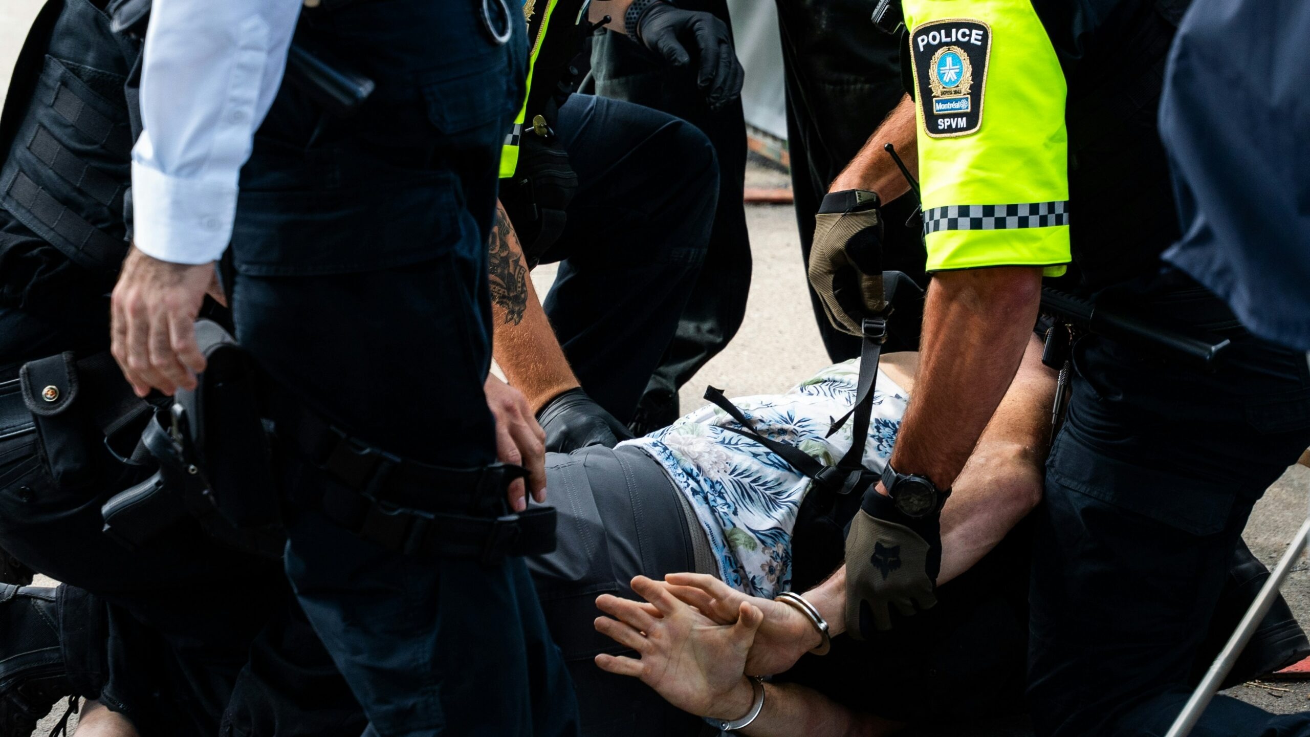 Police officers arresting a man on the ground.