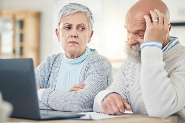 Laptop stress and budget with a senior couple feeling anxiety about their pension or retirement fund Computer debt finance or accounting with old people problem solving their savings or investment