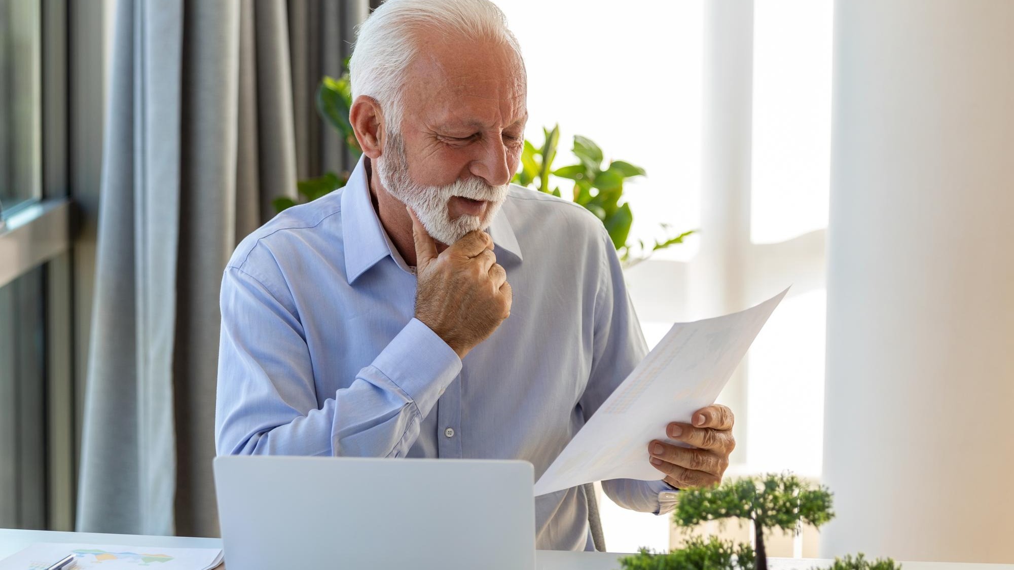 Financial advisor businessman using his laptop and doing some paperwork while sitting at desk and working