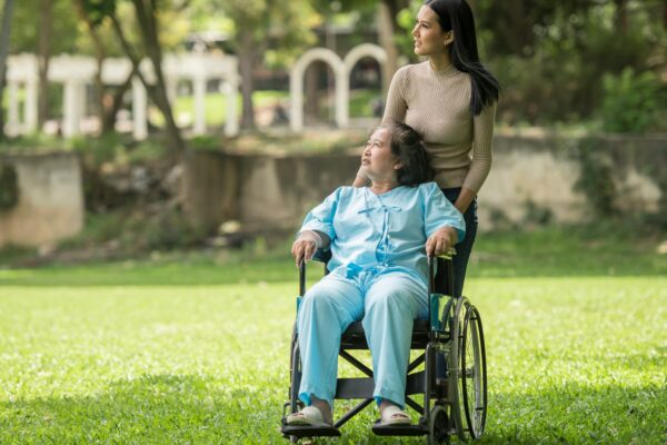 A woman in a wheelchair standing next to a man in a park
