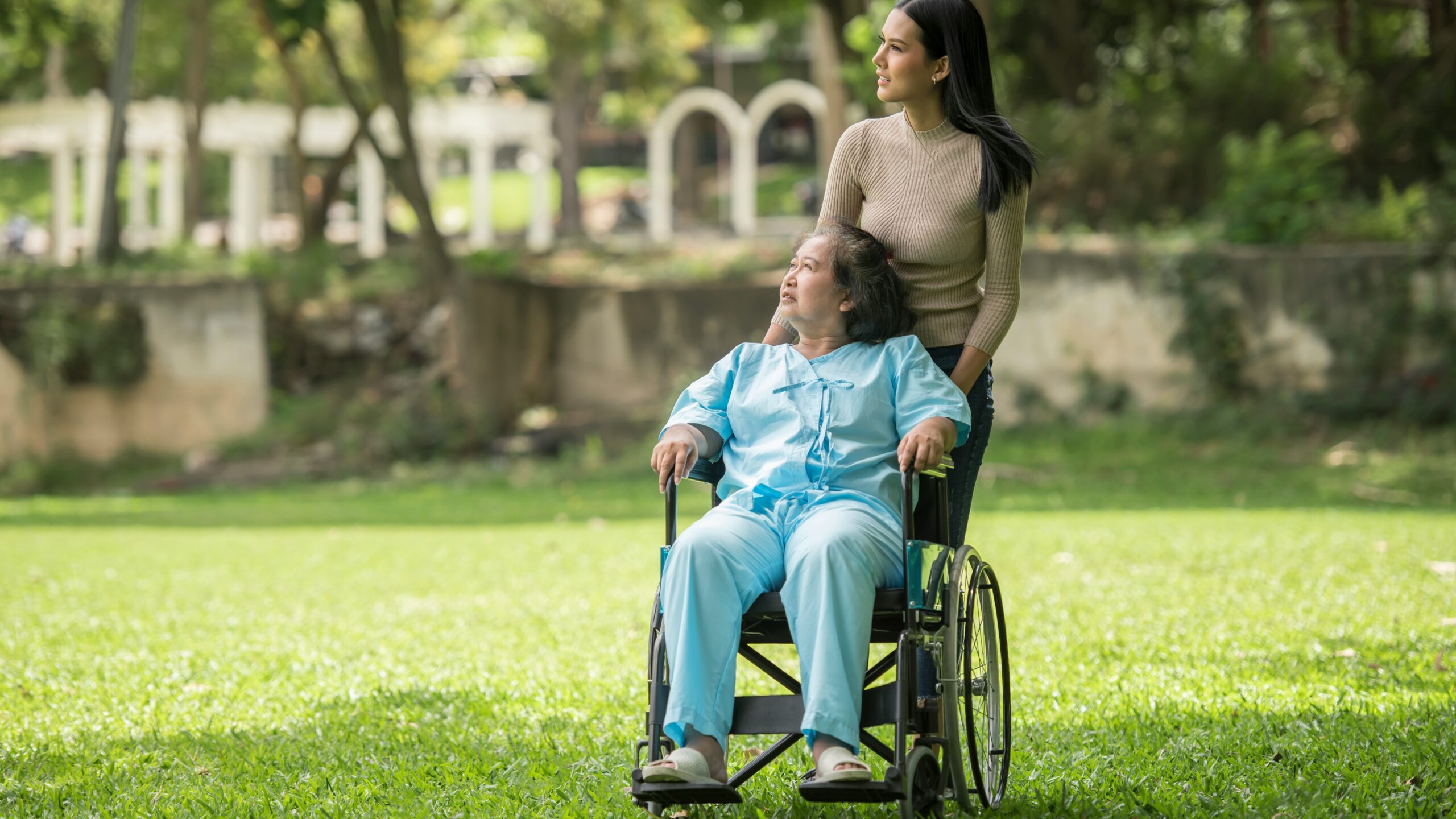 A woman in a wheelchair standing next to a man in a park