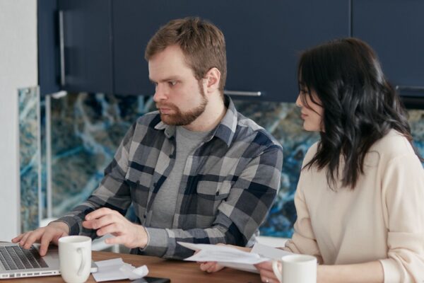 A couple working together on a laptop managing finances at home, showcasing teamwork and concentration.