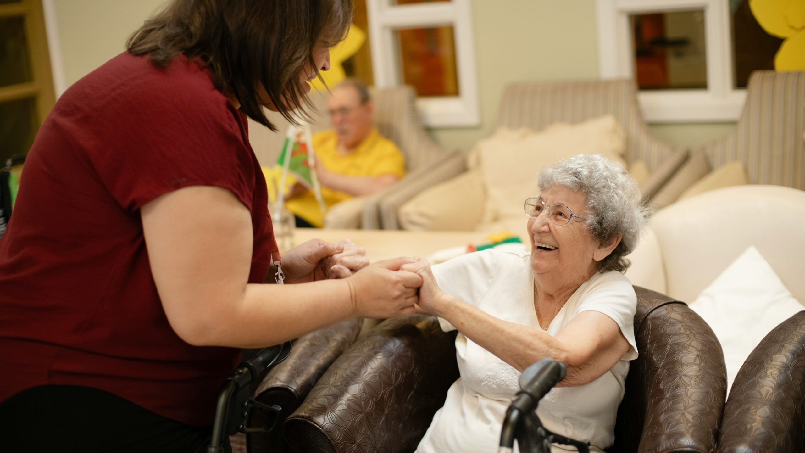 Caregiver assists elderly woman with walker.
