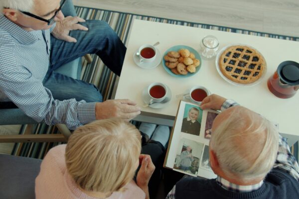Seniors looking at a photo album with tea and snacks