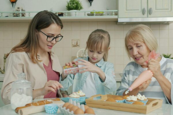 Three women baking and decorating cupcakes in a kitchen