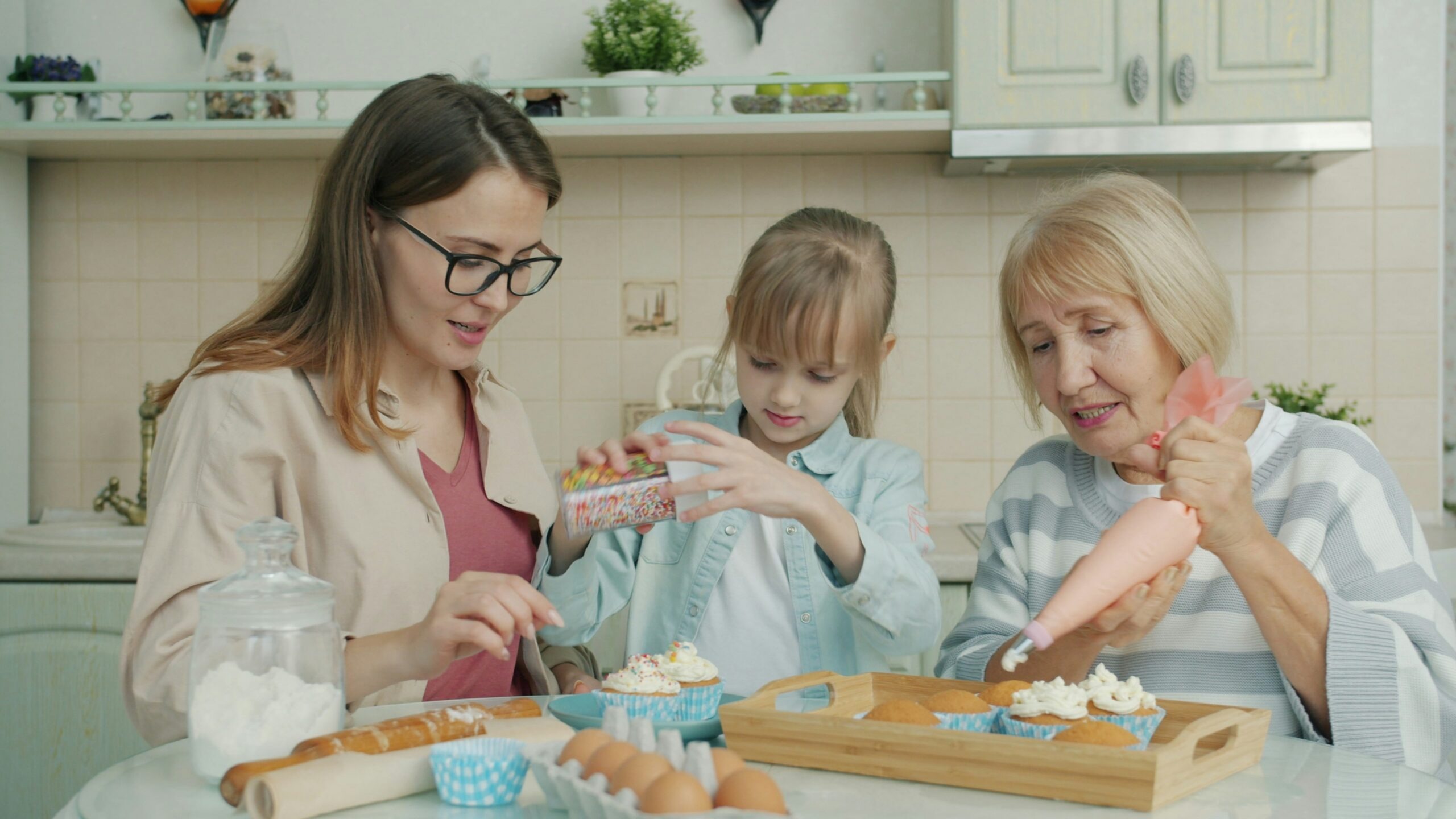 Three women baking and decorating cupcakes in a kitchen