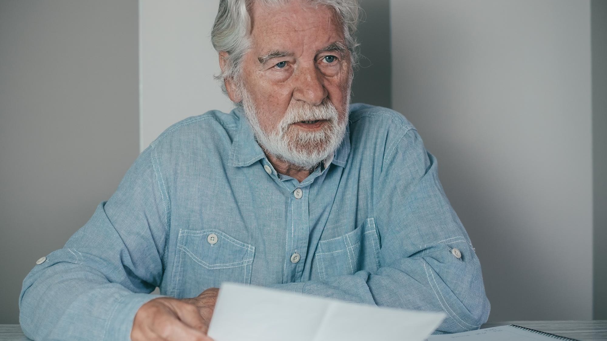 Senior bearded financial advisor man consulting documents sitting indoor at home