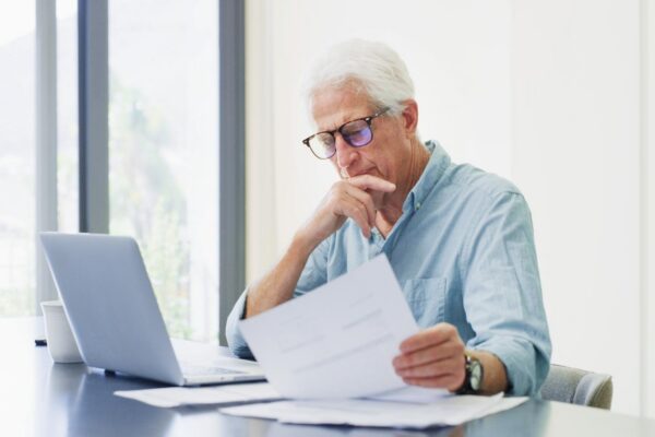 Laptop thinking and old man with documents financial analysis and bills with retirement fund Pc home and senior person with paperwork debt and asset management with insurance policy and decision