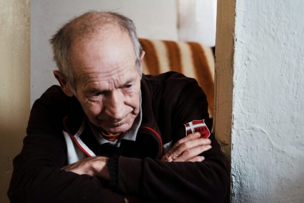 man in black jacket sitting on brown wooden chair