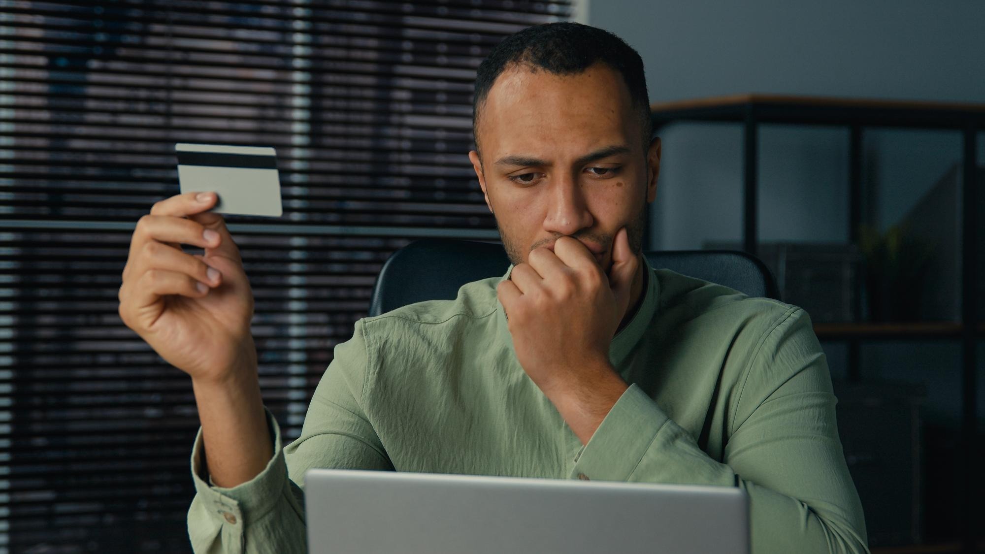 Puzzled confused african american man pay remote credit card using laptop problem with online payment bank failure annoyed guy male enter wrong password worried overspend money on electronic account