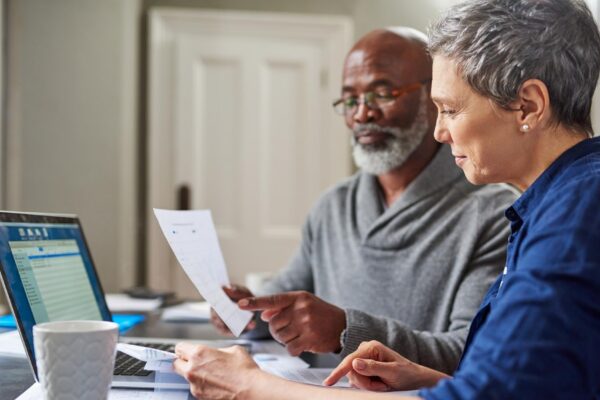 Laptop documents and finance with a senior couple busy on a budget review in the home together Accounting taxes or investment planning with a mature man and woman looking at insurance or savings
