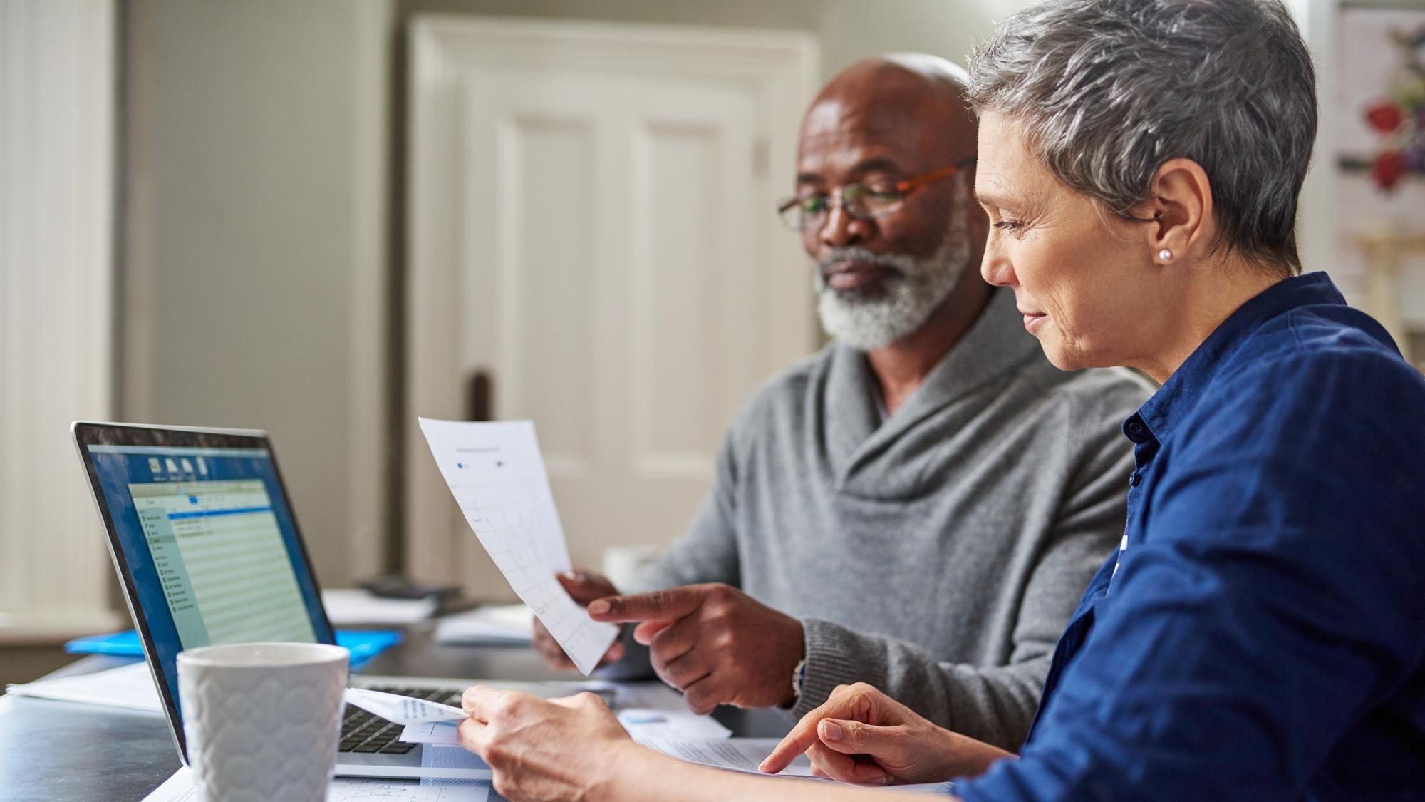 Laptop documents and finance with a senior couple busy on a budget review in the home together Accounting taxes or investment planning with a mature man and woman looking at insurance or savings