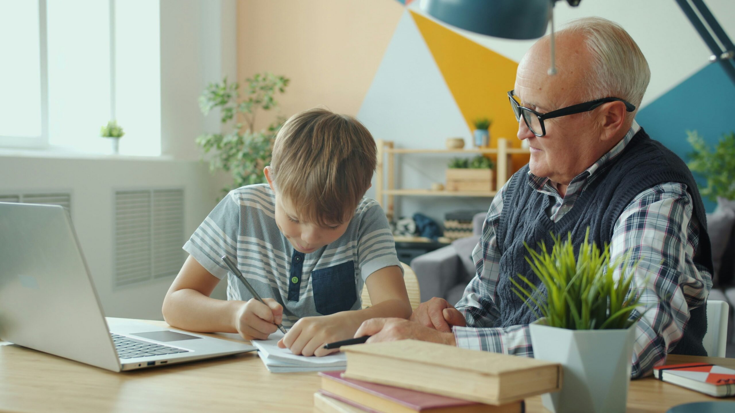 Grandfather helps grandson with homework at desk