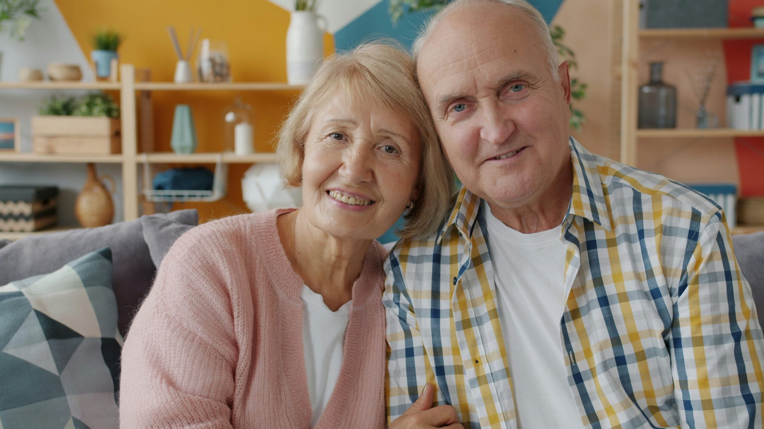 Elderly couple smiling together on a couch