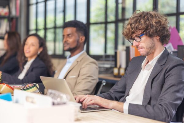 Colleagues in a boardroom discussion, seated at a table together, swapping ideas and strategizing project strategy. In the office, young business professionals