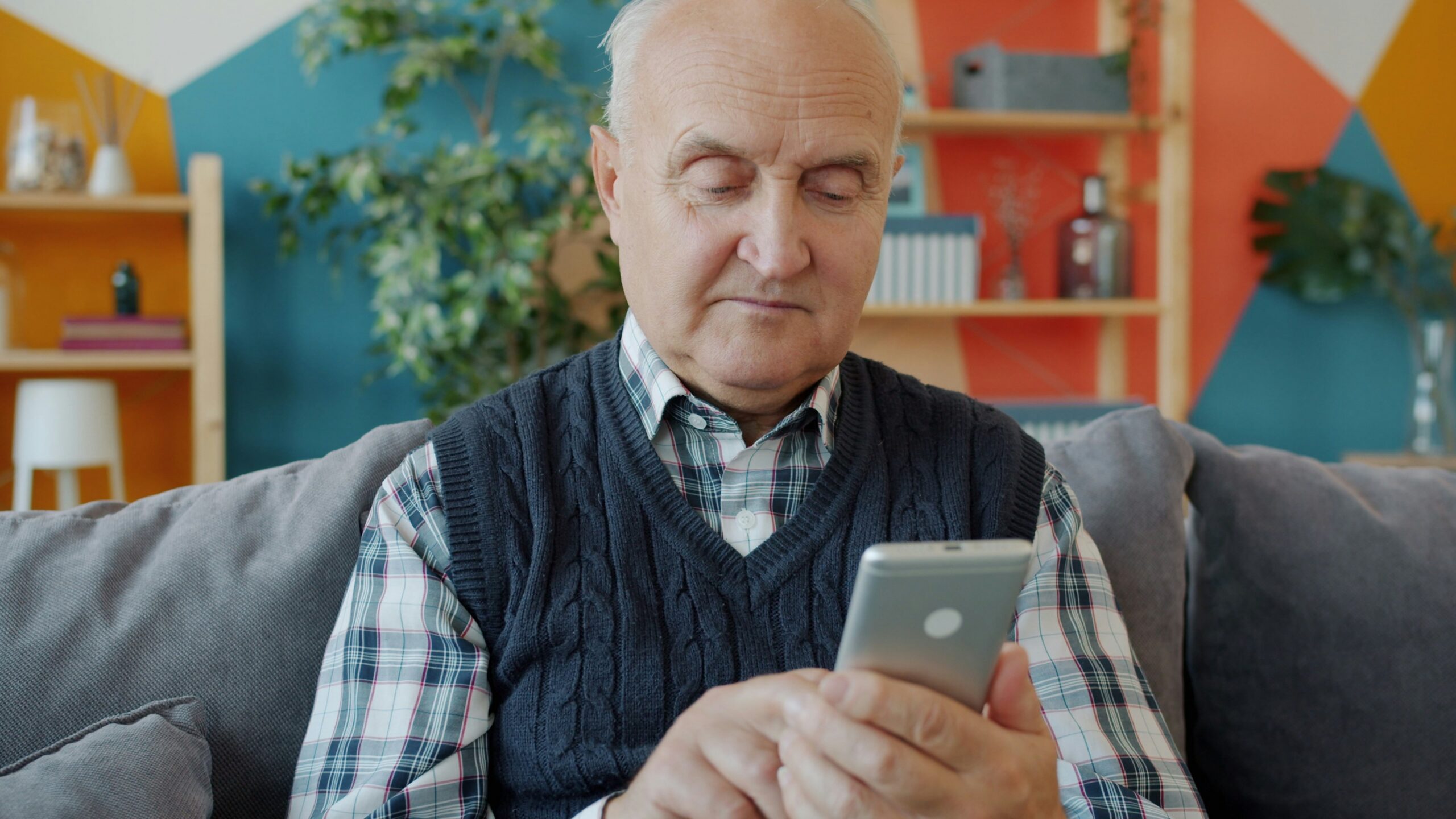 Elderly man using a smartphone on a couch