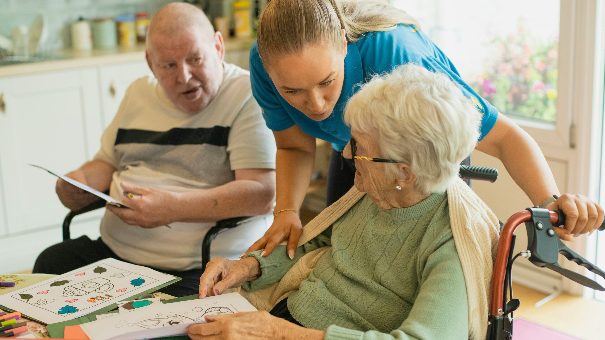 Caregiver assisting elderly couple with coloring