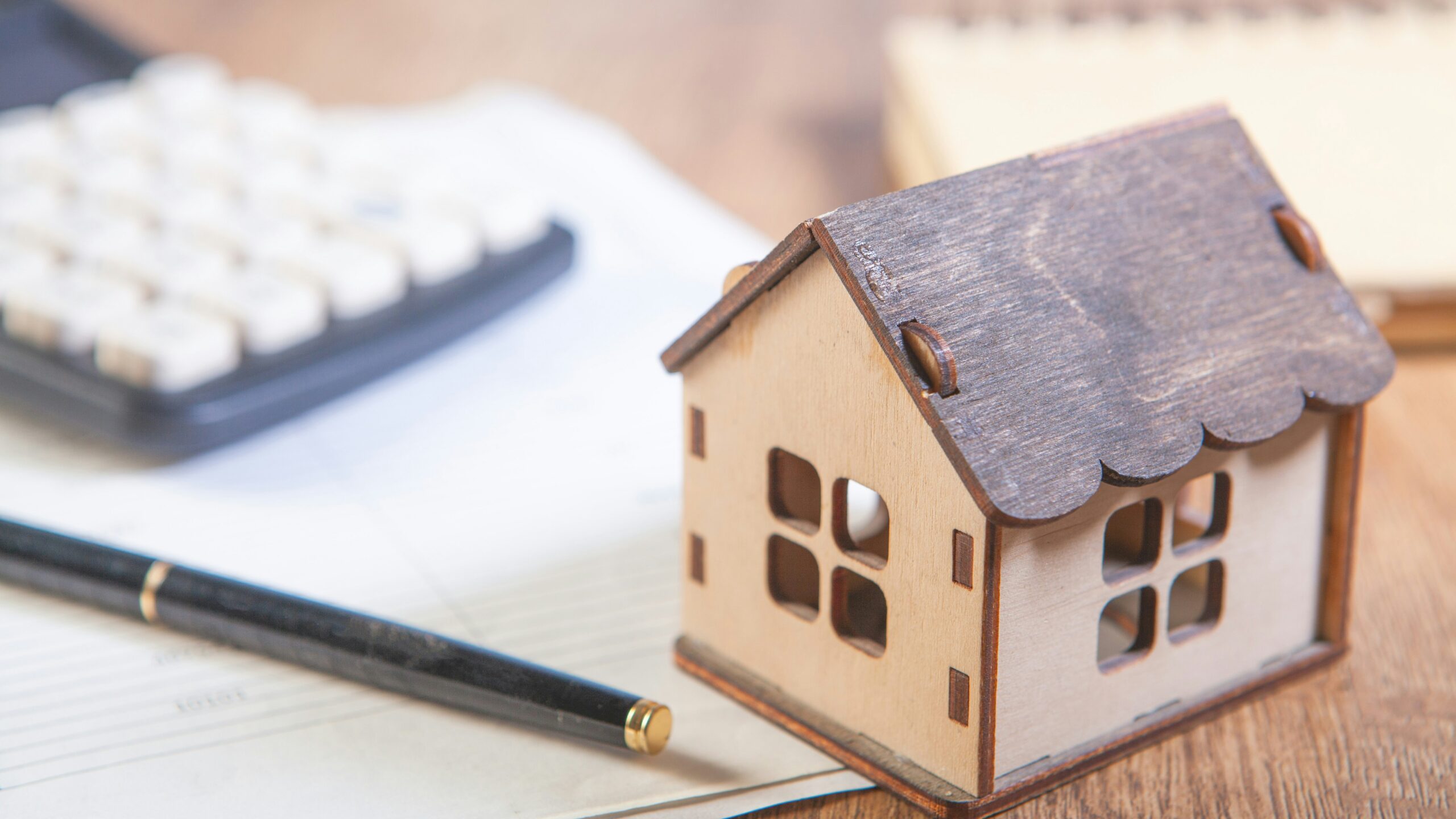 Model house with calculator and pen on desk