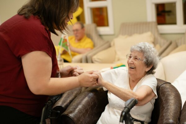 Caregiver assists elderly woman with walker.