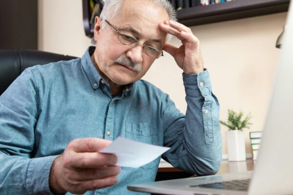 a man holding a pen and looking at a laptop