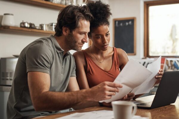 Its never too late to start Cropped shot of a couple using their laptop and going through paperwork at home
