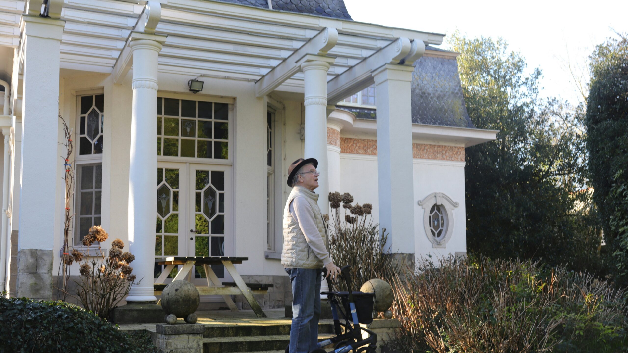 Elderly person with walker in front of a house