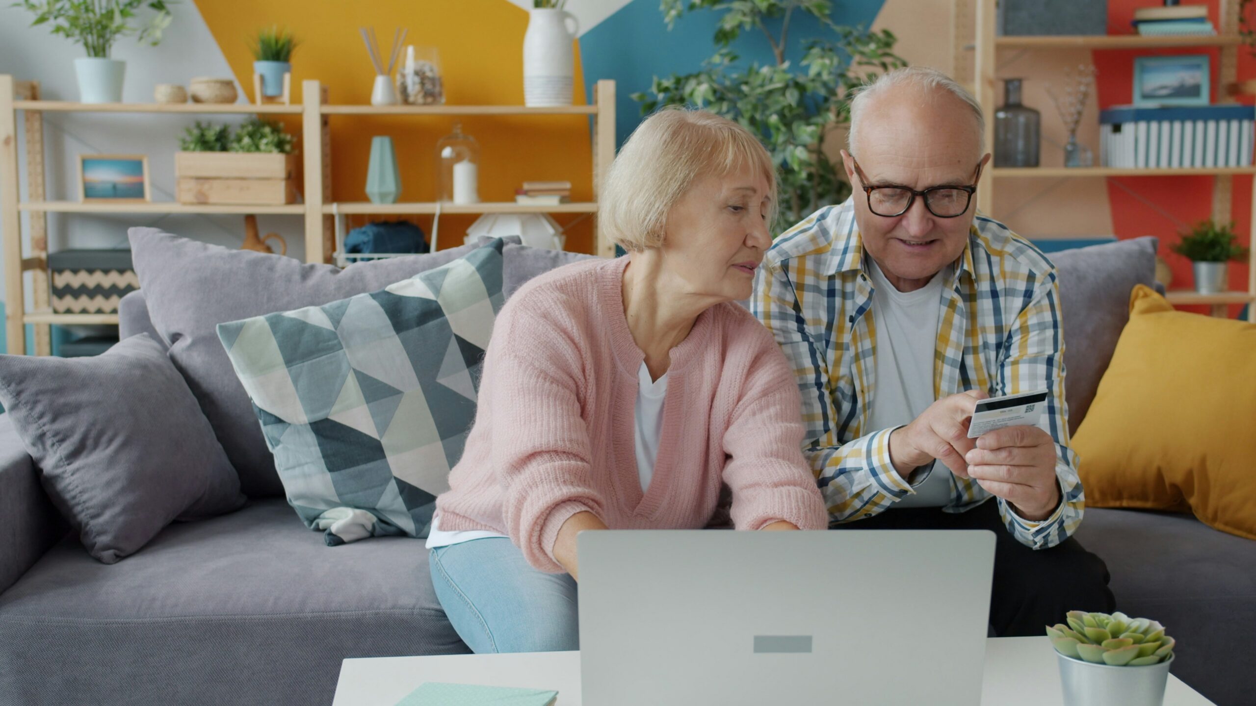 Elderly couple shopping online with credit card and laptop