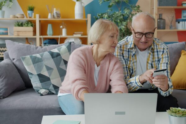 Elderly couple shopping online with credit card and laptop